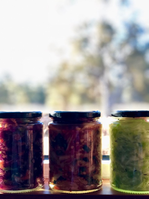 three jars of fermented vegetables sitting on a window sill